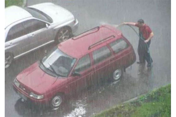 man washing his car in the rain