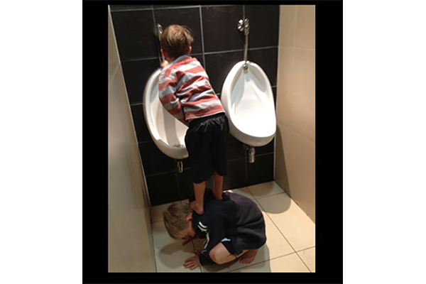 boy peeing whilst standing on friend